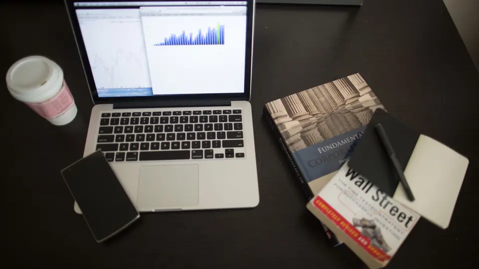 Clean desk with laptop displaying compound interest charts and notebook