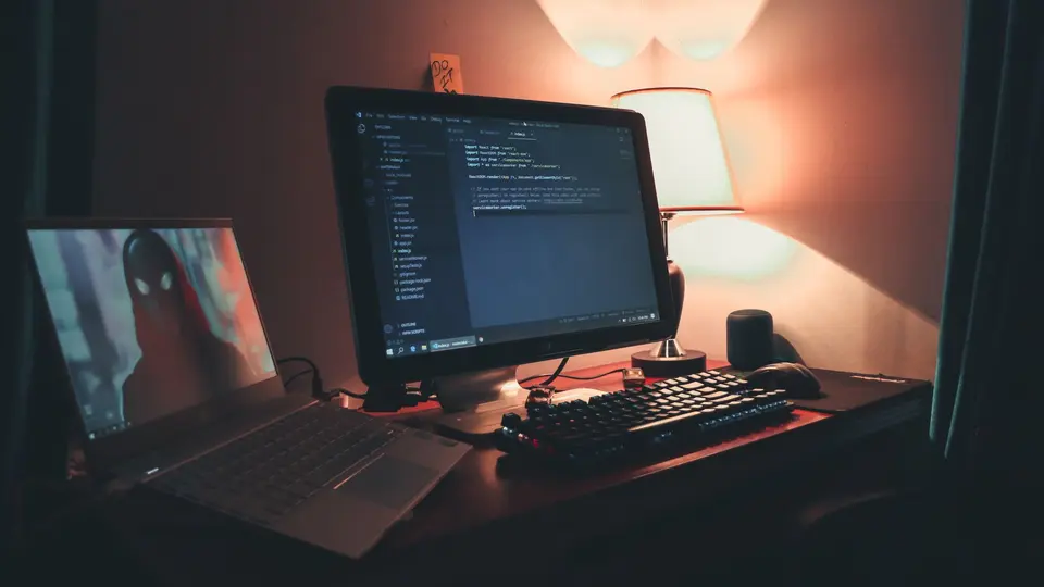 Minimalist desk with ultrawide curved monitor showing clean web application codebase