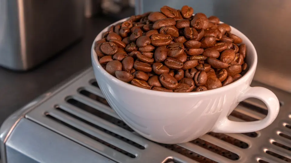 Close-up of espresso machine, coffee beans, and receipt in quiet office kitchen